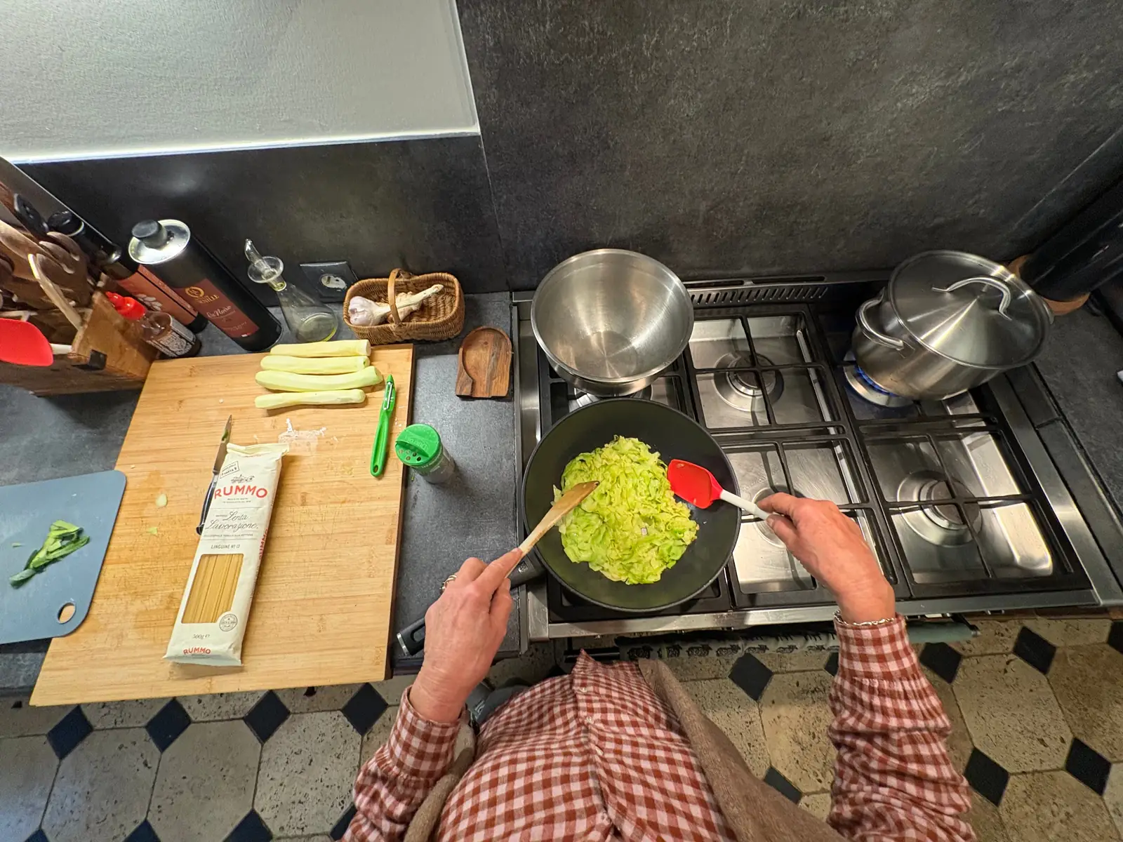 First-person view of two hands cooking zucchini in a pan, the type of egocentric data EgoVista collects from contributors.